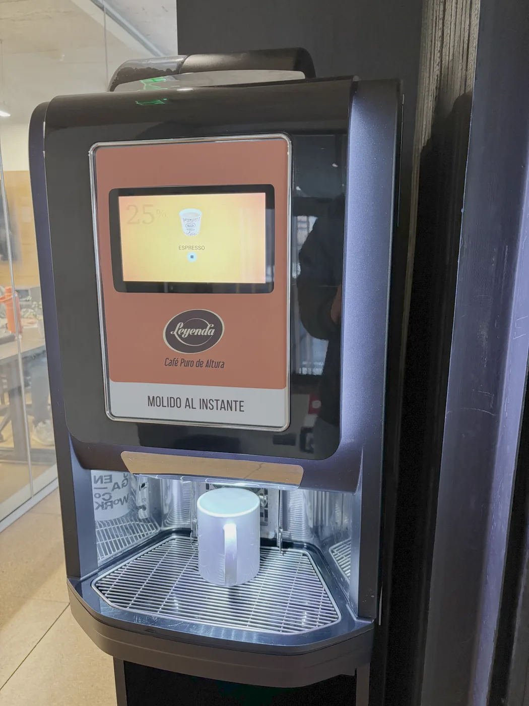 Máquina de café de grano de la oficina, con una taza servida